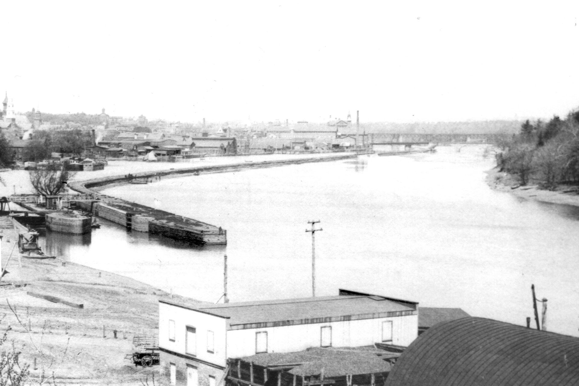 Here the northern terminus of the D&R is seen where the canal met the Raritan River in New Brunswick. The footbridge seen by the outlet allowed mainland access for the mules and tenders.