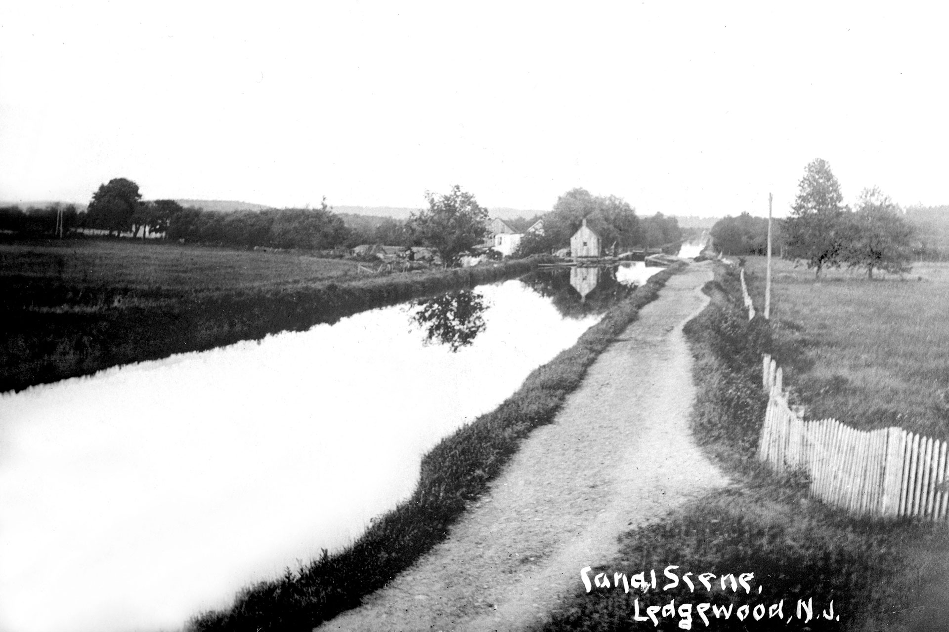 Looking east from the Main Street bridge in Ledgewood, the canal passes through Lock 1 East and heads toward Kenvil. This scene shows how rural Ledgewood was during the canal days.