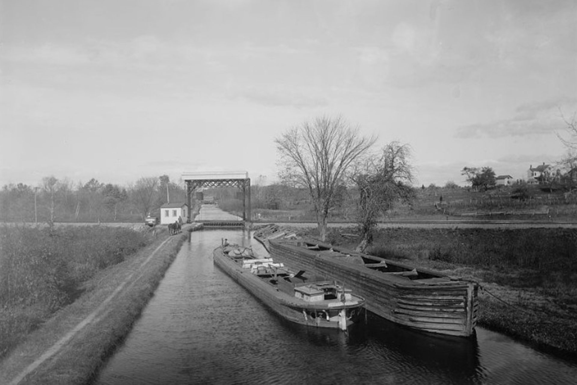 A loaded boat passes a moored light boat as it makes its way up the Pompton Feeder toward the lift bridge for the DL&W RR.