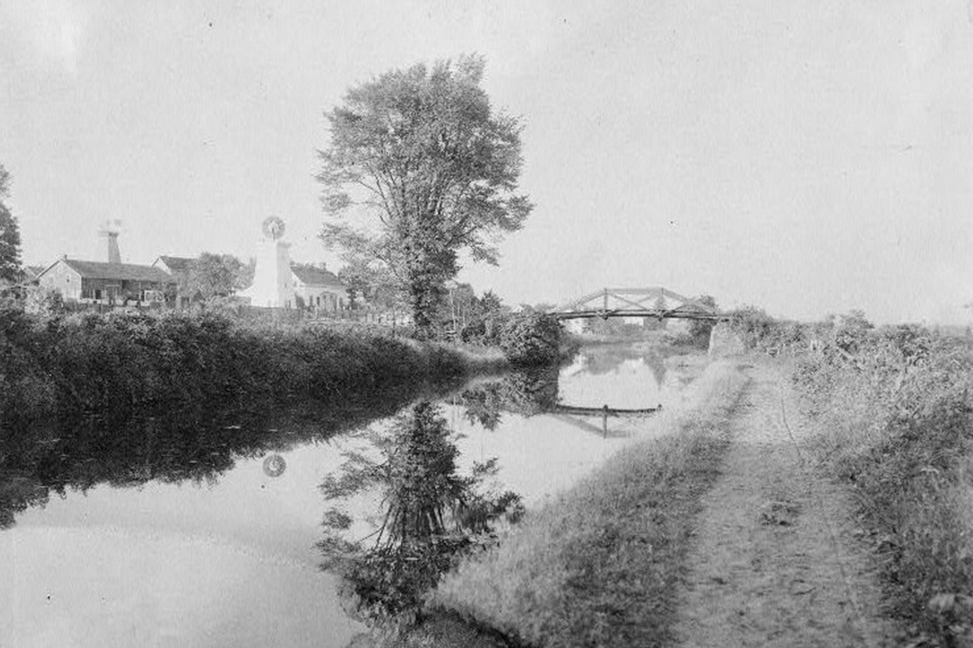 This view looks north on the canal at Clifton, where the canal follows the general path of the Garden State Parkway today. The house with the windmill still exists on Broad Street.