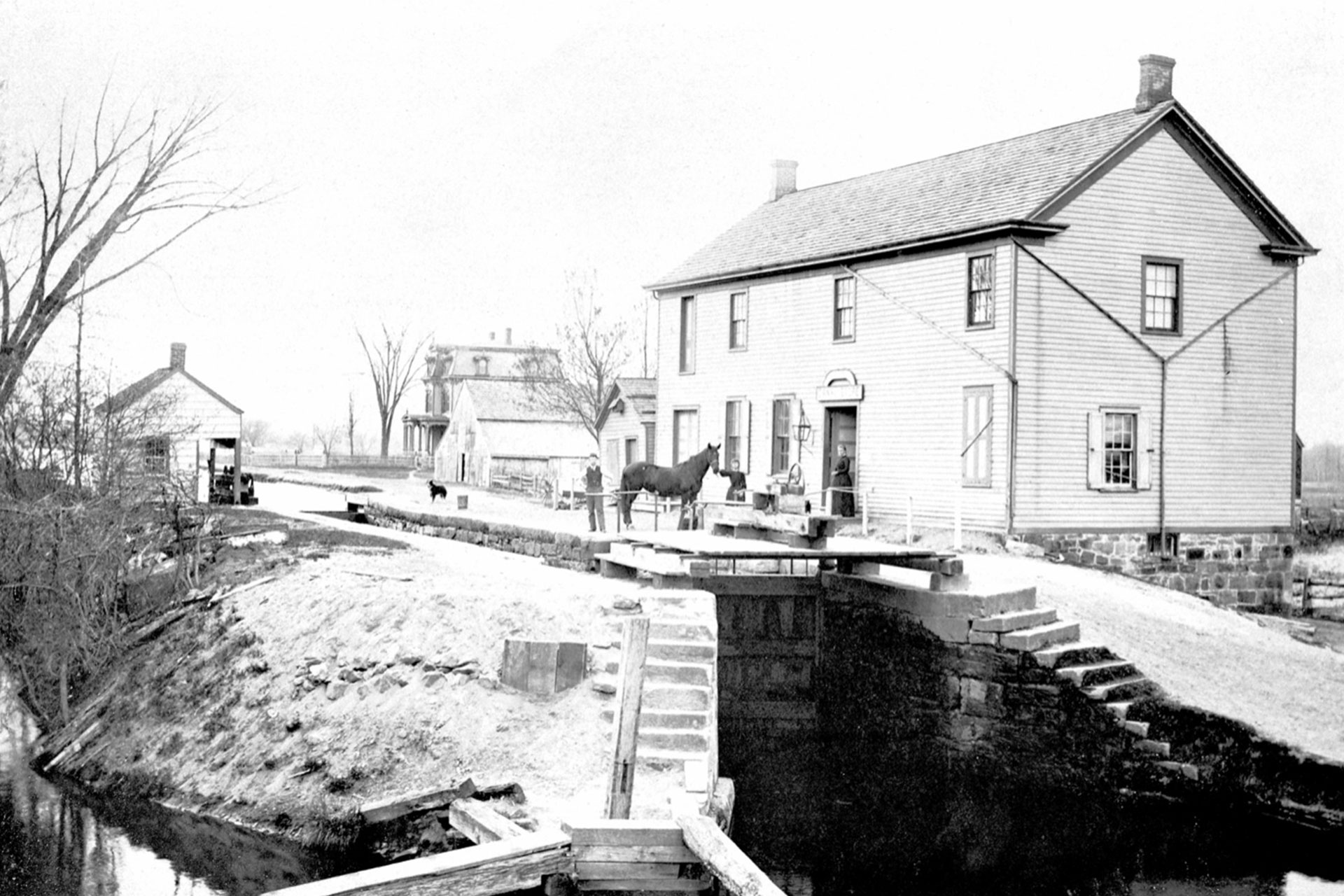 Taken from the Main Street bridge (today Rte 202), this view looks at the foot of Lock 14 East in Lincoln Park. The building to the right of the canal was a general store.