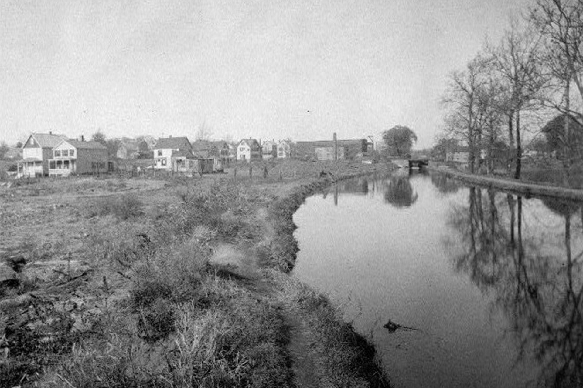 This view, looking west on the canal, shows Lock 15 East in the distance. The two houses seen on the left still exist.